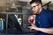 Freelancer man with plastic cup of fresh beverage in hand works with laptop. Businessman in glasses drinks juice for