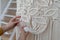 Freelancer woman working on half-finished macrame piece, weaves lamp shade for chandelier. Women hobby