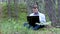 Freelancer working on laptop under the tree in the woods