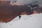 freeride skier descends from a mountain slope against the backdrop of coniferous trees