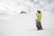 Freeride snowboarder dressed in yellow sportswear looking at mountain