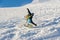 Freeride snowboarder rolls on a snow-covered slope leaving behind a snow powder against the blue sky