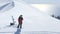 Freerider girl in sports outfit, glasses and helmet standing on snowy peak in mountain resort. Aerial view snowboarder with snowbo