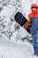 Freerider with a snowboard in overalls stands on top of a snowy mountain