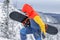 Freerider with a snowboard in overalls stands on top of a snowy mountain