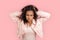 Freestyle. African girl in denim jacket standing isolated on pink messing hair looking camera angry close-up