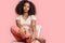 Freestyle. African girl sitting on chair isolated on pink relaxed close-up