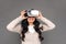 Freestyle. Mature lady in virtual reality headset standing isolated on grey watching video excited