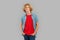 Freestyle. Teen blond boy standing isolated on gray hands in pockets confident