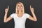 Freestyle. Woman standing on black wall pointing up smiling excited close-up