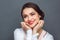 Freestyle. Woman standing isolated on grey holding face smiling delightful close-up