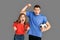 Freestyle. Young couple standing isolated on grey with football ball screaming cheering team excited