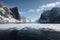 freezing fiord, with view of towering cliffs, and distant peaks visible in the background