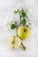 Freh ripe green apple decorated with beautiful apple blossom on white wooden table