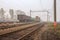 Freight terminal of railway trains. Railway tracks, cars and locomotive in fog.