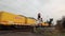 A freight train with many DHL containers passes a level crossing with closed barrier gate and red warning sign