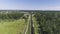 A freight train moves along a rail in the middle of a green forest and meadows.