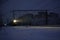 Freight train at night. The headlights and locomotive headlights illuminate the falling snow. Russia