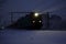 Freight train at night. The headlights and locomotive headlights illuminate the falling snow. Russia