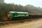 Freight train transports sand with freight wagons in a sand pit in cloudy foggy weather.