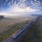 A freight train travels through a foggy forest.