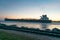 A freighter moving through the water with railroad tracks beside it.