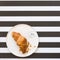 French croissants on a plate on striped background, top view. Delicious breakfast. Have a nice day