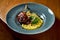 French cuisine - duck leg confit with polenta and caramelized pear, served in a blue plate on a wooden background. Restaurant food