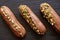 French dessert eclairs or profiteroles with milk chocolate glaze and pistachios on a black stone plate. Cakes with cream and