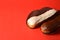 French desserts eclairs with white chocolate and dark chocolate on top filled with custard served on red background