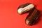 French desserts eclairs with white chocolate and dark chocolate on top filled with custard served on red background