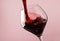 French dry red wine, pours into glass, trendy pink background, space for text, selective focus