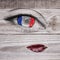 French flag on eye pupil with tear drop, realistic lips on wooden grey background