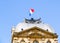 French flag flying in breeze above pediment of classical building