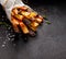 French fries,  baked fries from different types and colors of potatoes sprinkled with herbs and spices on a black background