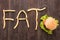 French fries with burger forming word fat on wooden background