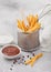 French fries chips in strainer basket with salt and tomato ketchup on light background