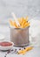 French fries chips in strainer basket with salt and tomato ketchup on light background