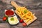 French fries on chopping board with tomato sauce and mayonnaise