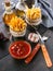French fries in a metal mug with tomato sauce on a rustic background. Portion potato fries. Tasty Snack from fast food. Fork,
