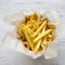 French fries in paper box over white wooden background, top view, top view. From above, overhead