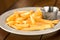 French fries on a plate with ketchup. French fries are served on a tray with or without sauce. On a wooden table.