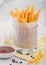 French fries potato chips in glass with tomato ketchup and pepper on yellow restaurant paper