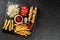 French fries potatoes, chicken skewers, pickles and cabbage, tomatoes and ketchup sauce on black stone background. Hot fast food