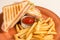 French fries and two sandwiches with cheese, sausage and lettuce leaves in a grunge plate, in the middle of a piano with ketchup s