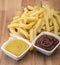 French fries on wooden board with catchup & mustard sauce