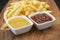 French fries on wooden board with catchup & mustard sauce