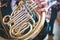 French horn on a wooden table. Beautiful polished musical instrument. Dark background