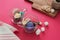 French macarons in glass cup with flowers and sugar on the pink background. Wooden desk with cookies. Front view.