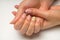 French manicure and nail gel Polish. Young, perfect, groomed woman`s hands with pink and white nail varnish bottles.